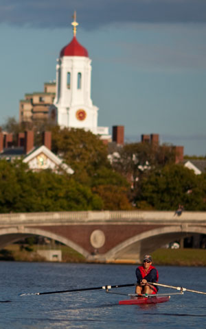 A man rowing on the Charles river with Harvard buildings in the background