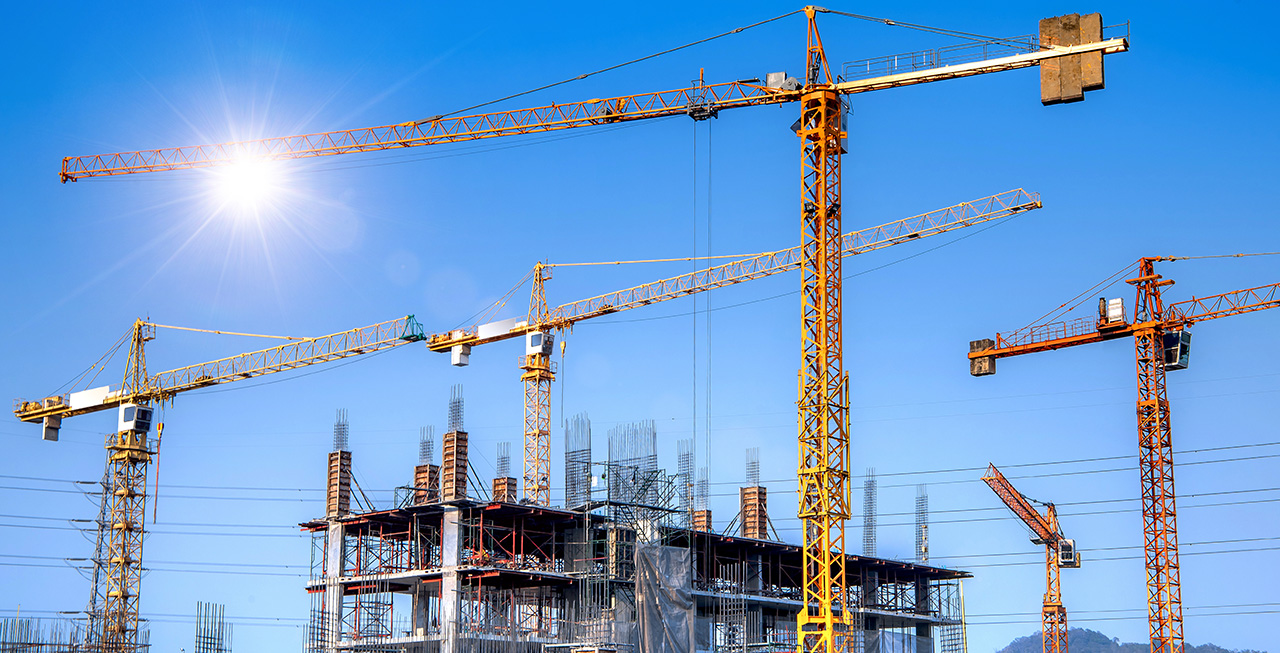 construction cranes against a sunny blue sky