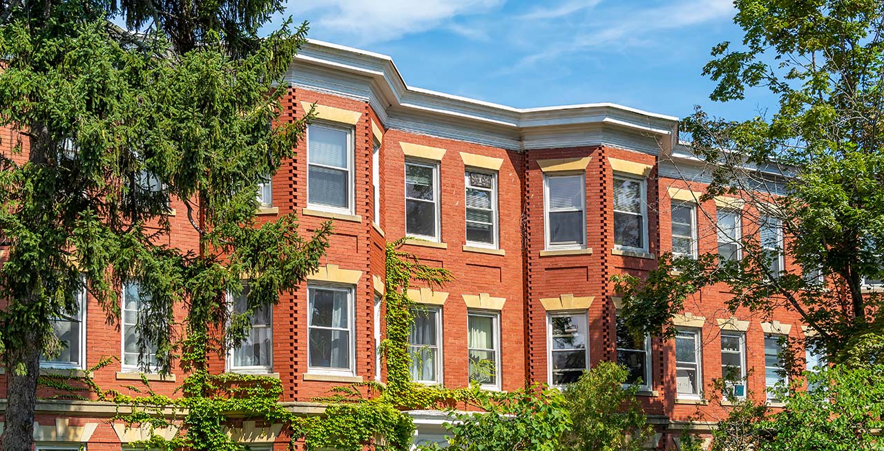 a series of red brick buildings with green ivy adorning them